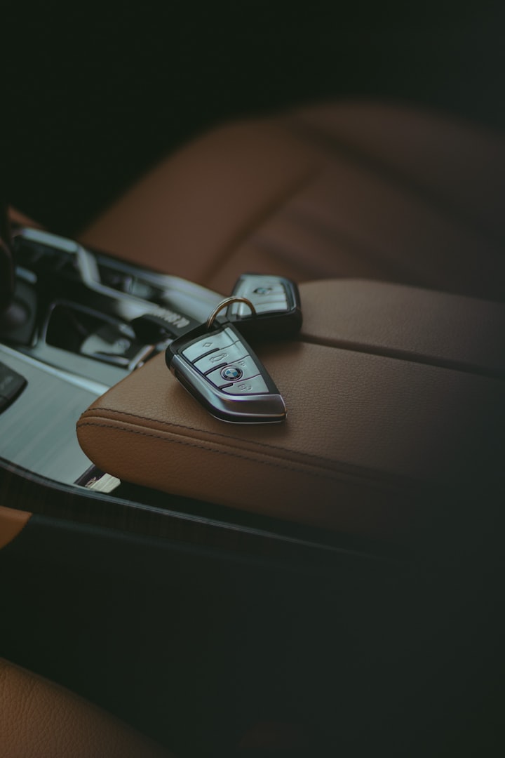 2 BMW car key fobs laid on brown leather armrest 