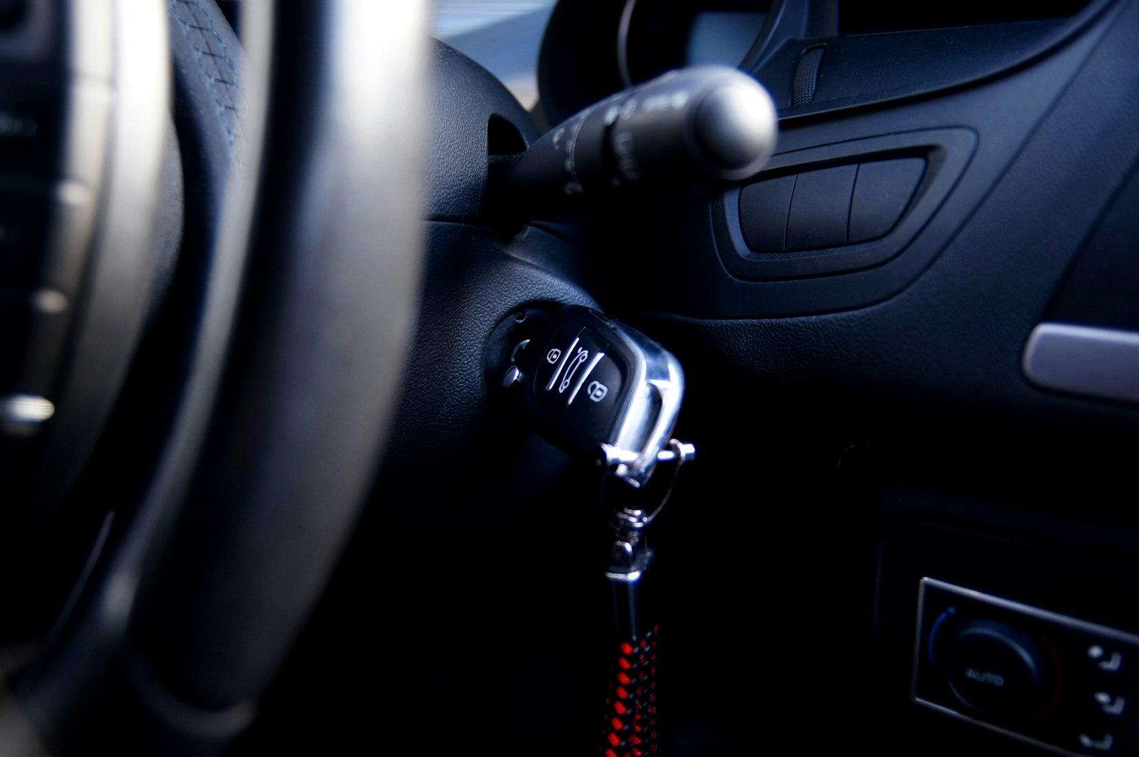 black and chrome car key inserted into ignition barrel with red key chain