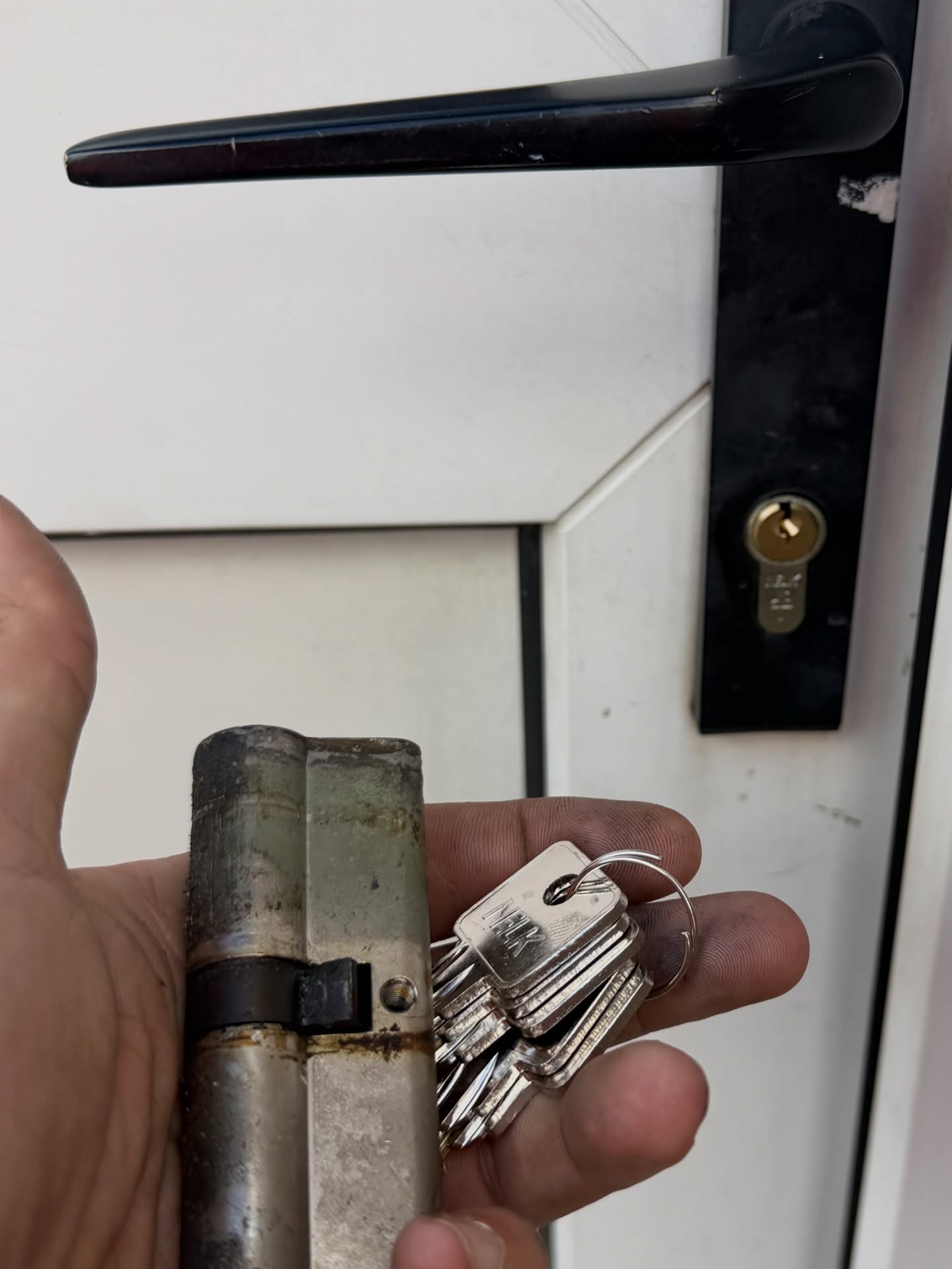 Outdated euro cylinder replaced with insurance compliant lock showing old and new lock with 5 keys in hand