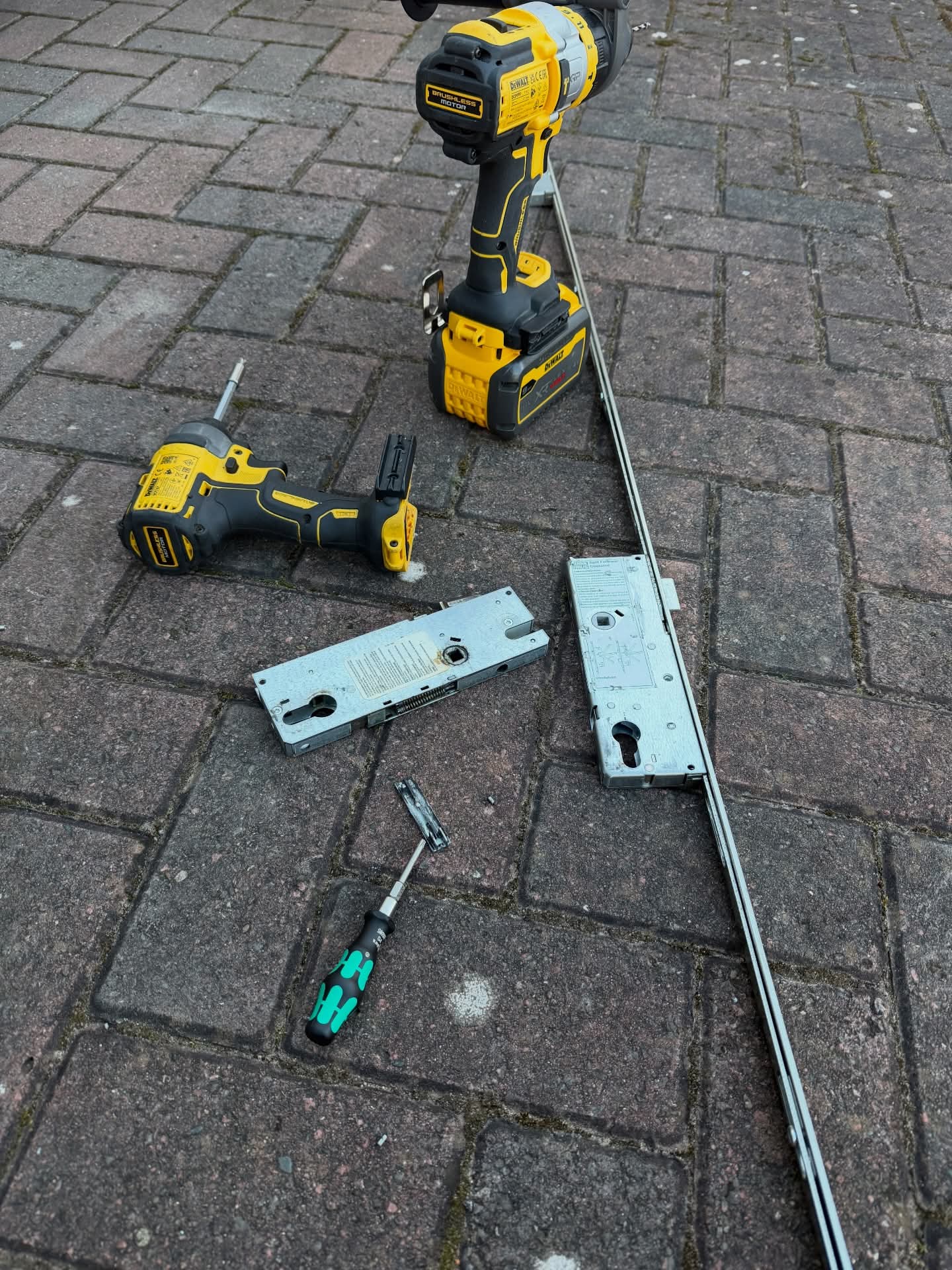 Emergency call out to Winkhaus lock mechanism showing old and new mechanisms laid on a block paved floor
