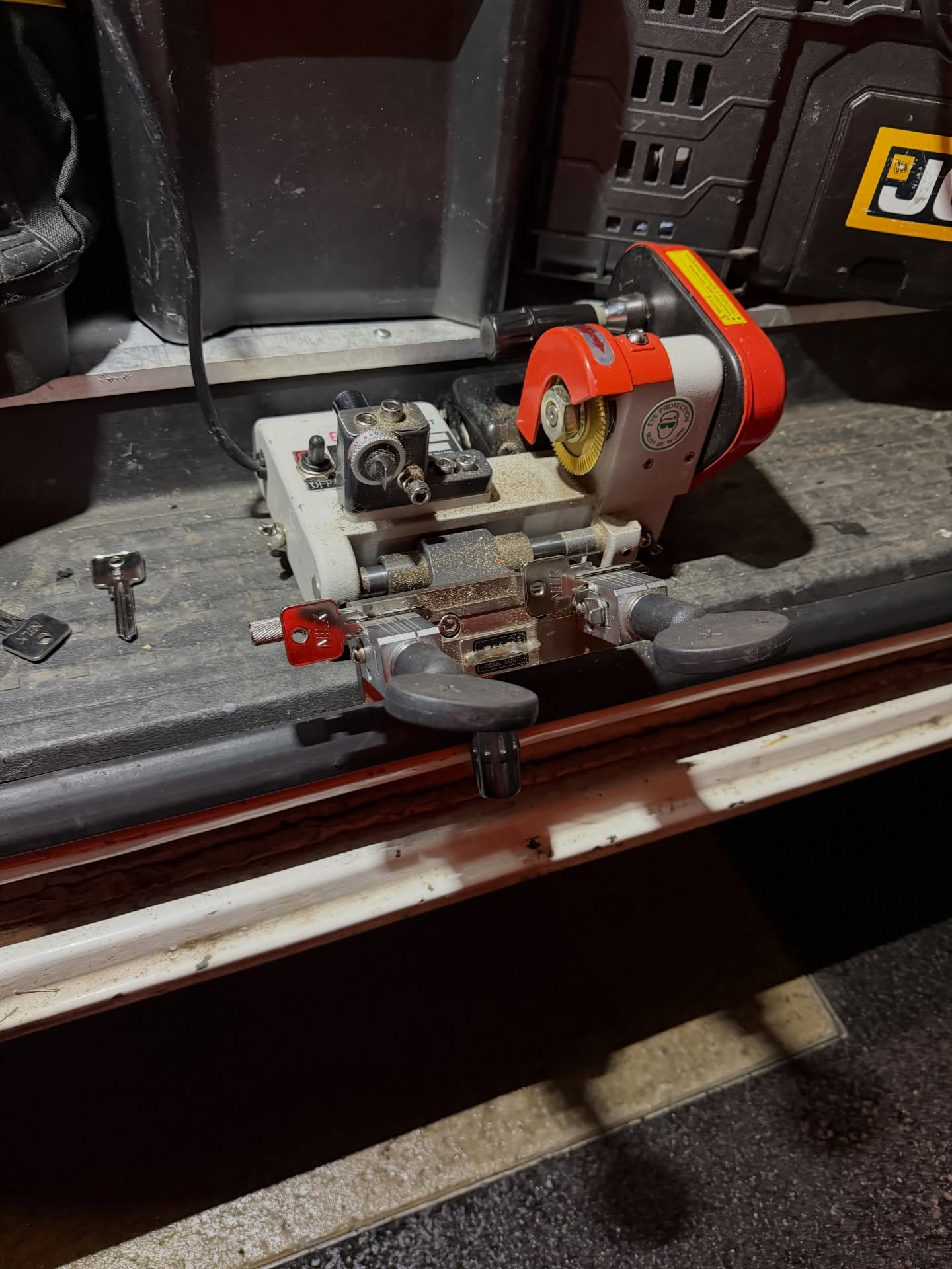 Key cutting machine fastened to grey work bench in back of Stay Safe Locksmiths van