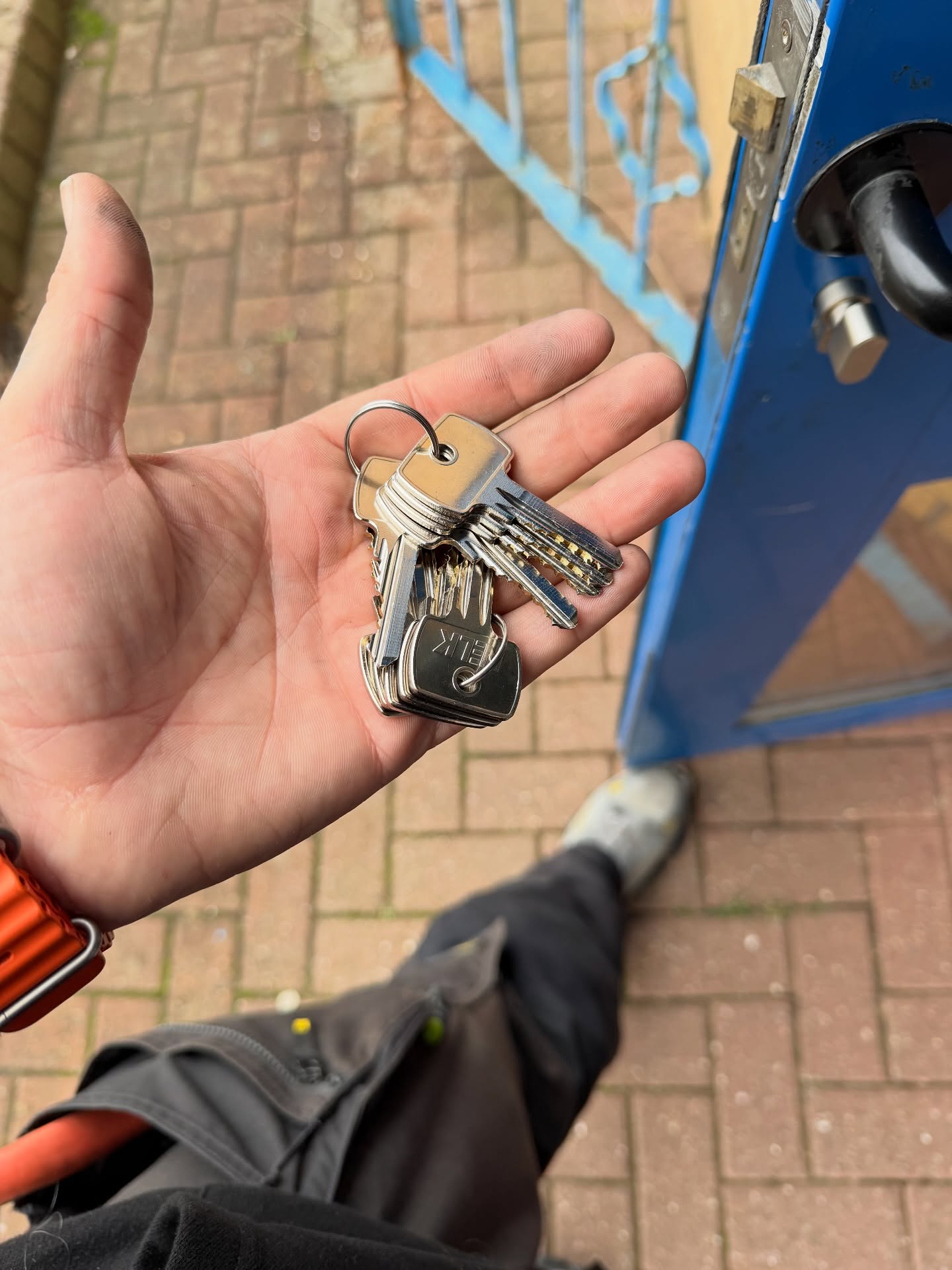 master key system installed in North Tyneside showing 10 keys being held in hand next to blue commercial door
