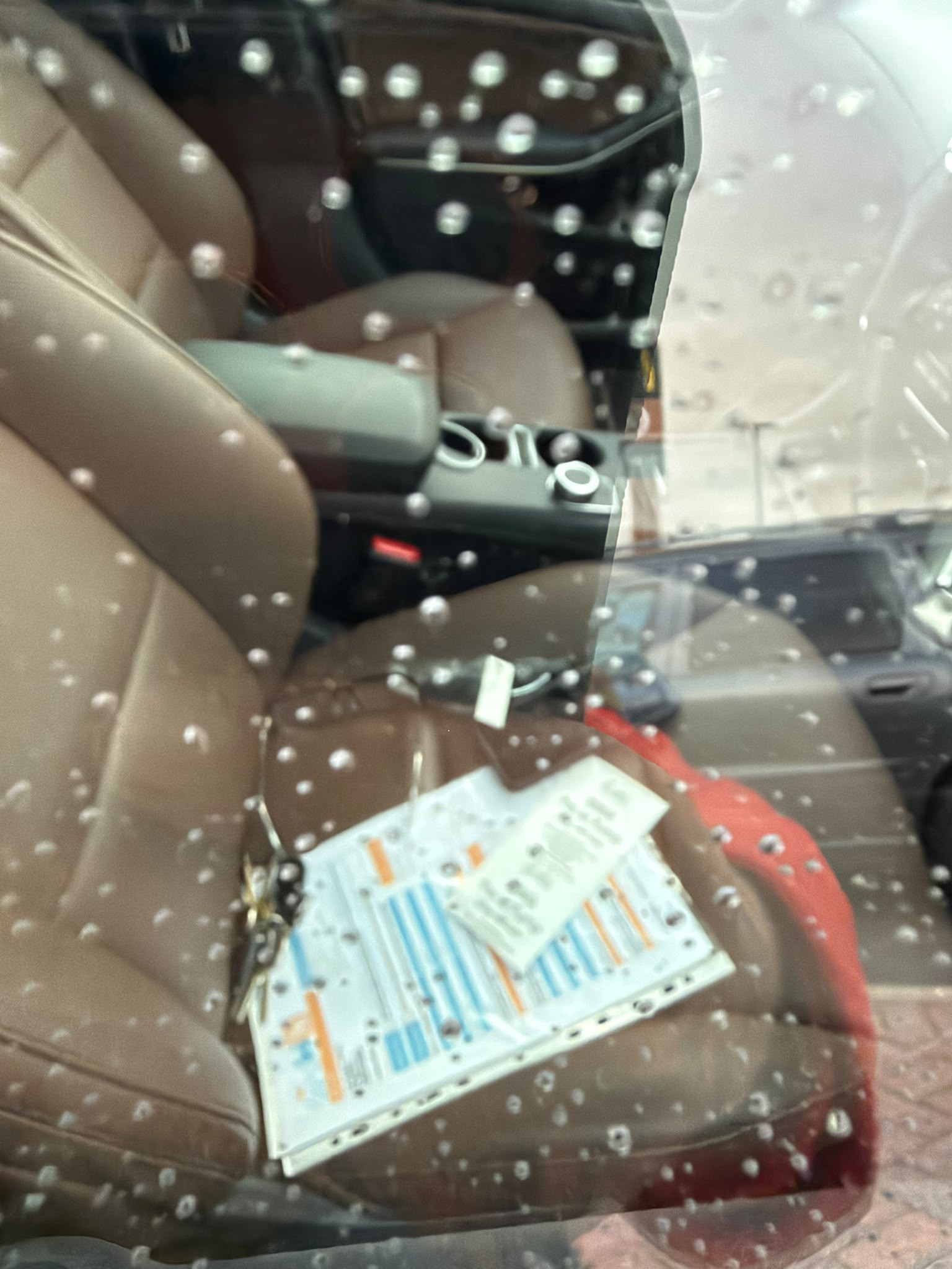 Keys locked inside of car sat on brown leather seat visible through car window